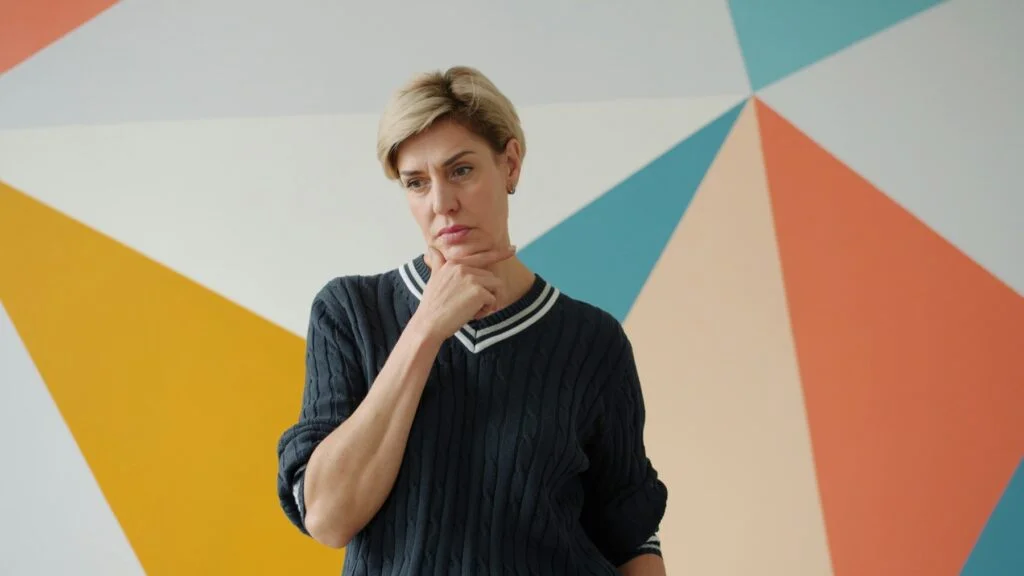 Woman in her fifties looking thoughtful with her hand on her chin