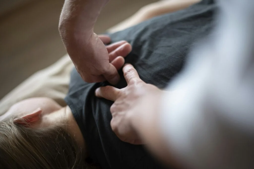 Hands pressing into a tight muscle knot in a person's upper back
