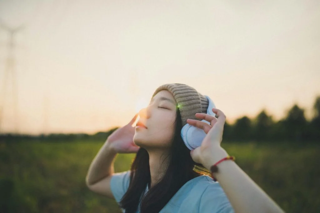 Woman with headphones and eyes closed listening to music outdoors