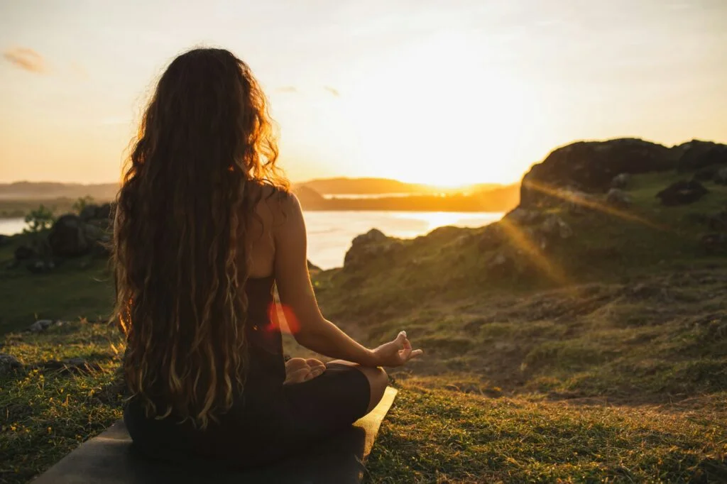 A woman meditating alone at sunrise in the mountains