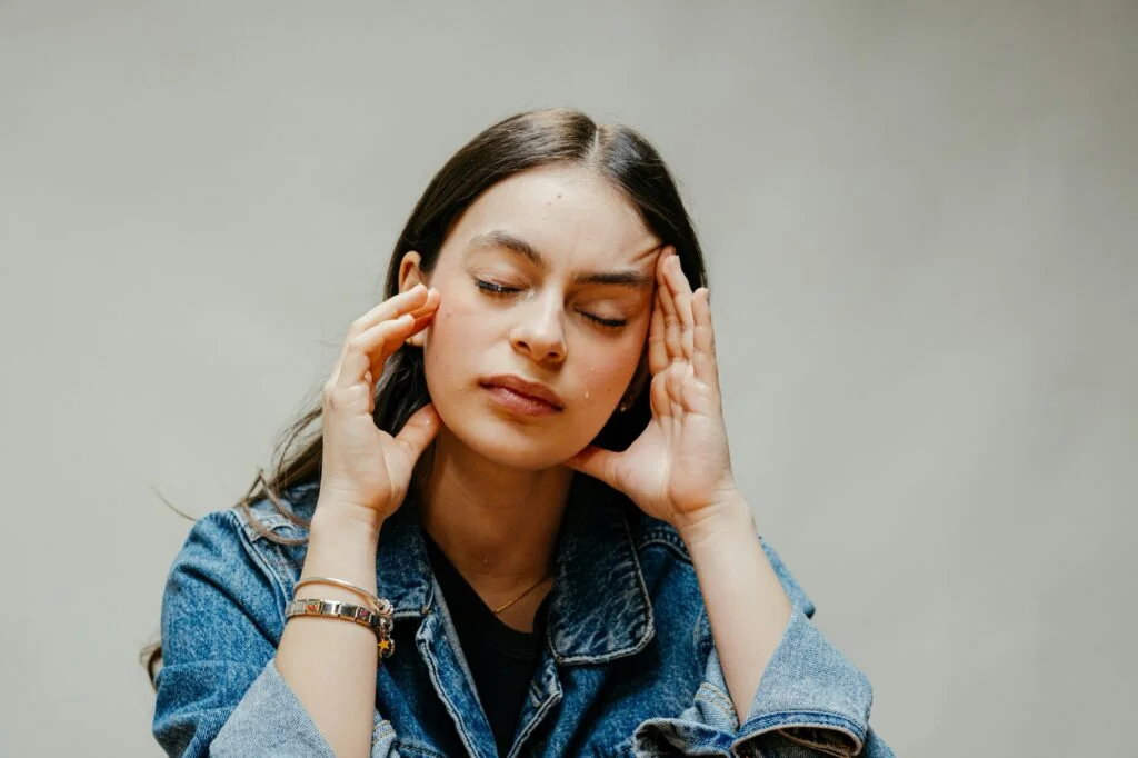 A woman with her eyes closed pressing her fingers to her temples