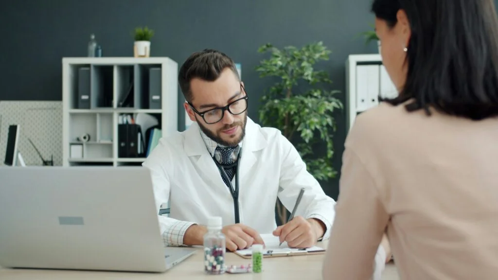 Young woman talking with a GP at a desk during an appointment
