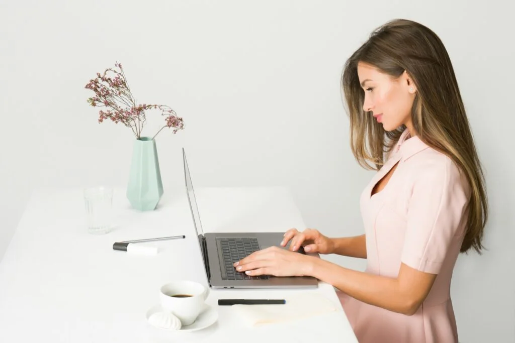 Woman sitting upright at a desk working on a laptop