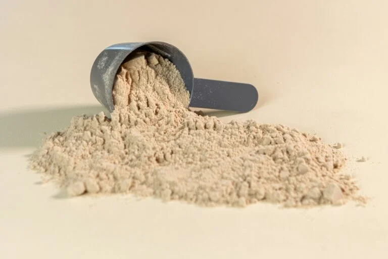 A scoop of fine mushroom powder spilling onto a light surface