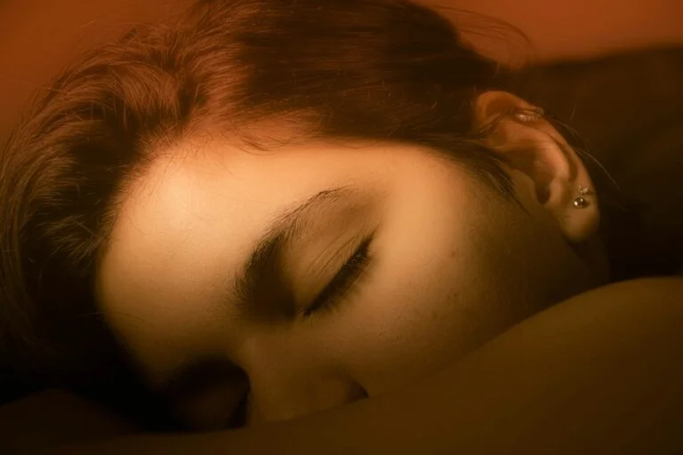 Close-up of a woman asleep with her eyes closed in warm light