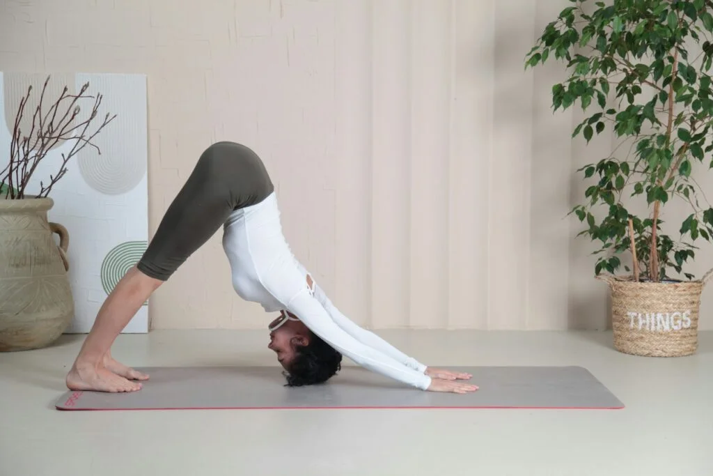 A woman doing a gentle downward dog stretch on a yoga mat at home
