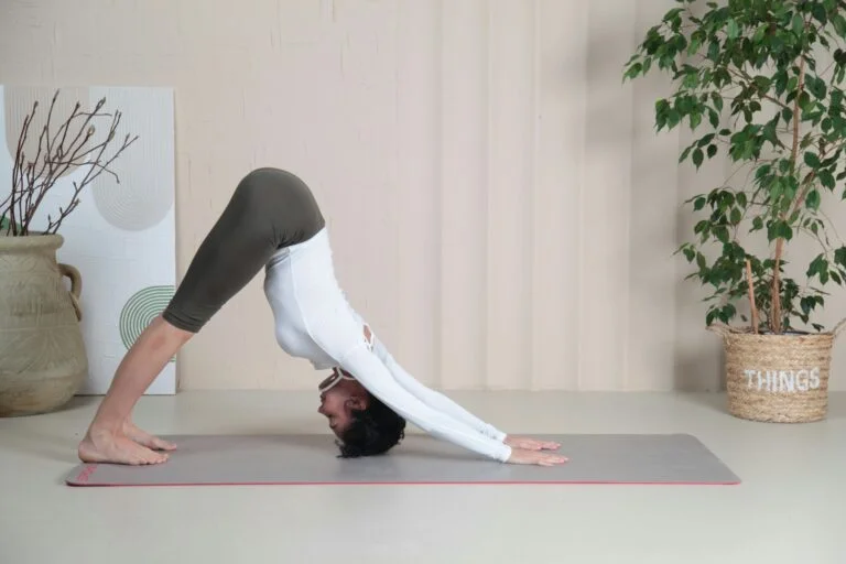 A woman doing a gentle downward dog stretch on a yoga mat at home