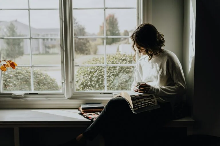 A woman reading by a window on a grey autumn morning