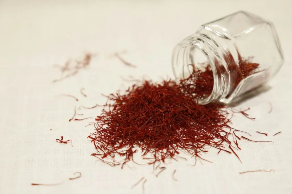 Saffron threads spilling from a small glass jar