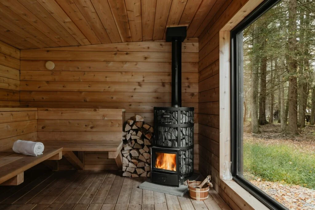 Wooden sauna with a wood-burning stove and a forest view