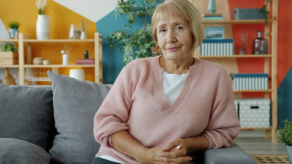 Older woman resting on a sofa at home, as shingles is most common in people over 50