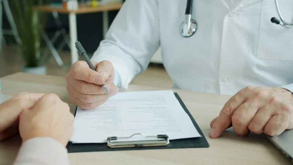 Doctor writing notes on a clipboard during an appointment