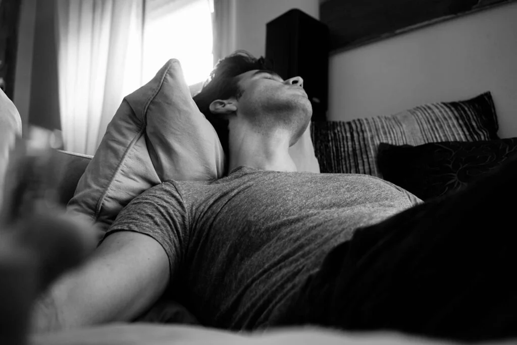 Man asleep on his back in bed with his head tilted back