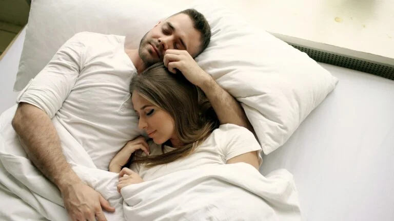 Couple asleep together in bed in the morning light