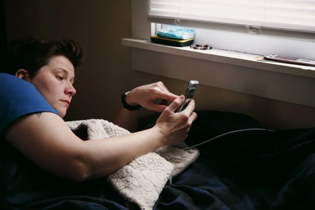 A person lying in bed looking at a phone