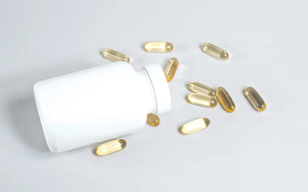 Supplement capsules beside a plain white bottle