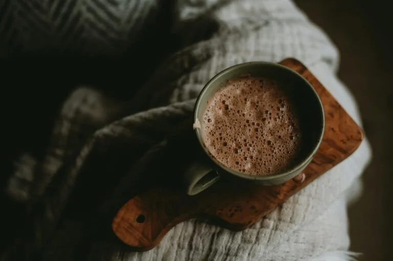 Mug of frothy mushroom hot chocolate on a wooden board