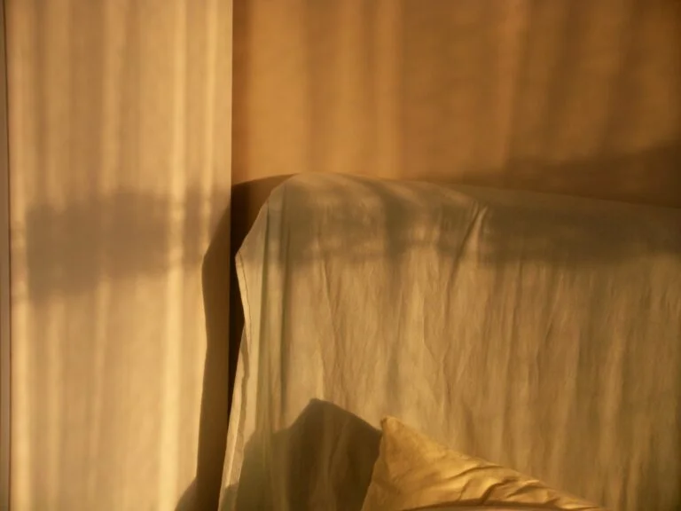 Warm golden morning light falling across a bed and curtains