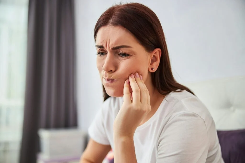 A woman holding her jaw in discomfort