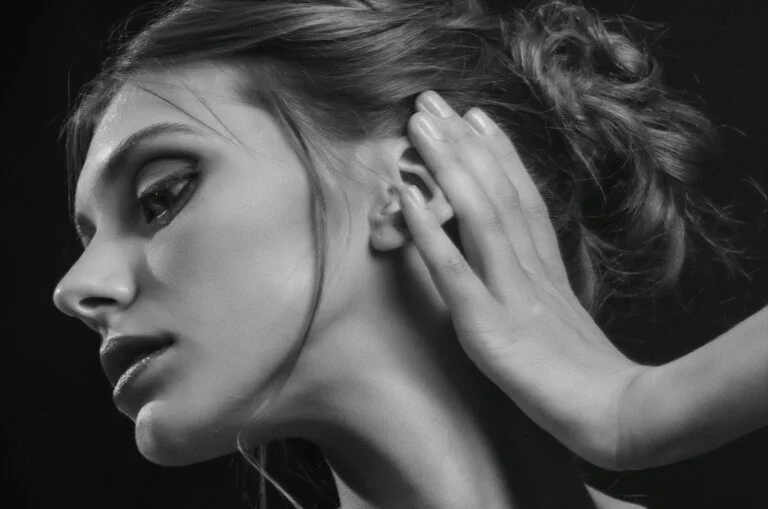 A woman cupping her hand behind her ear, black and white portrait