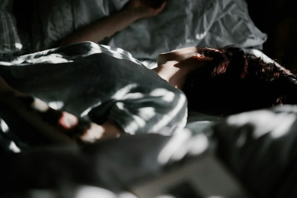 Person lying awake in bed in shadowy light