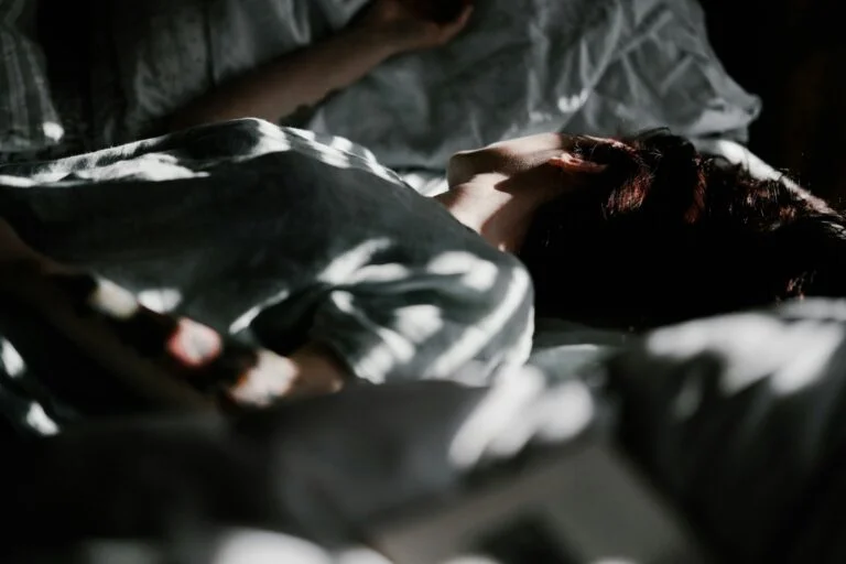 Person lying awake in bed in shadowy light