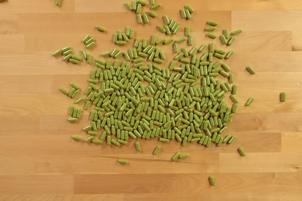 Green capsules scattered on a wooden table