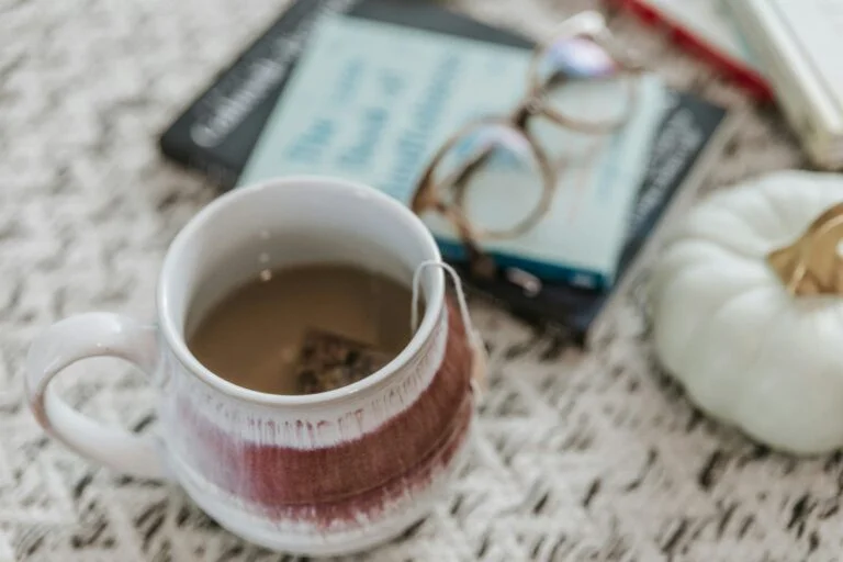 A mug of herbal tea with a tea bag beside a book