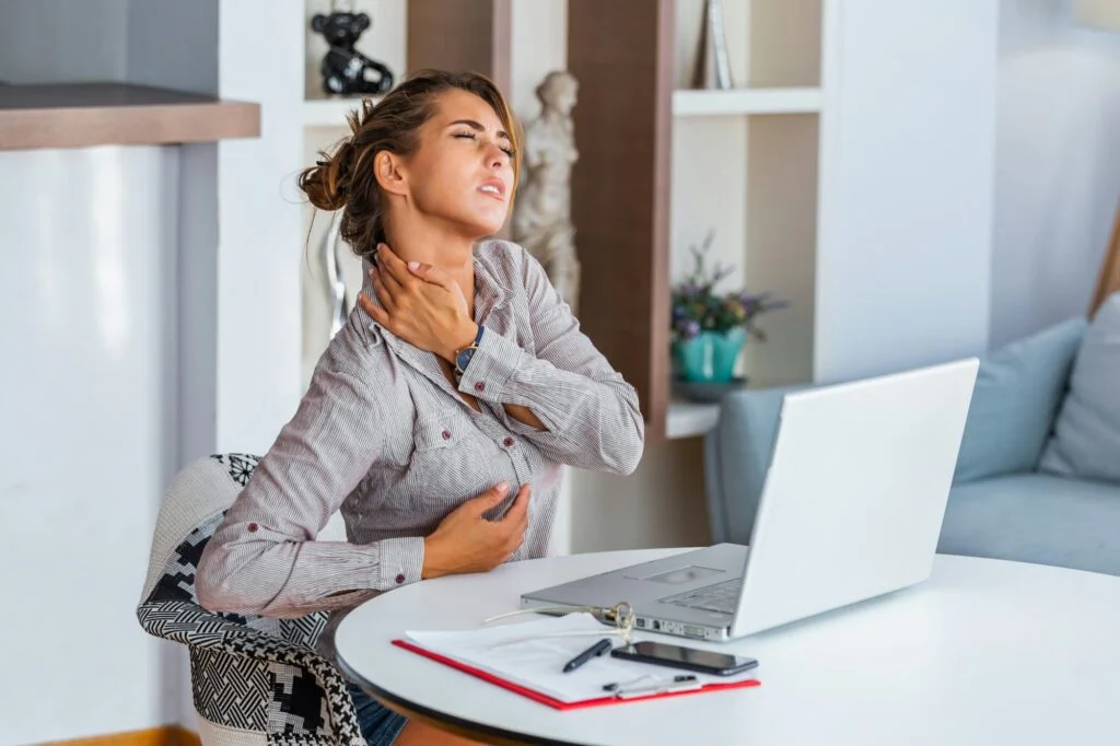 A tired woman at her desk holding her neck