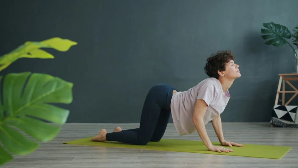 Woman doing a cat-cow back stretch on a yoga mat at home