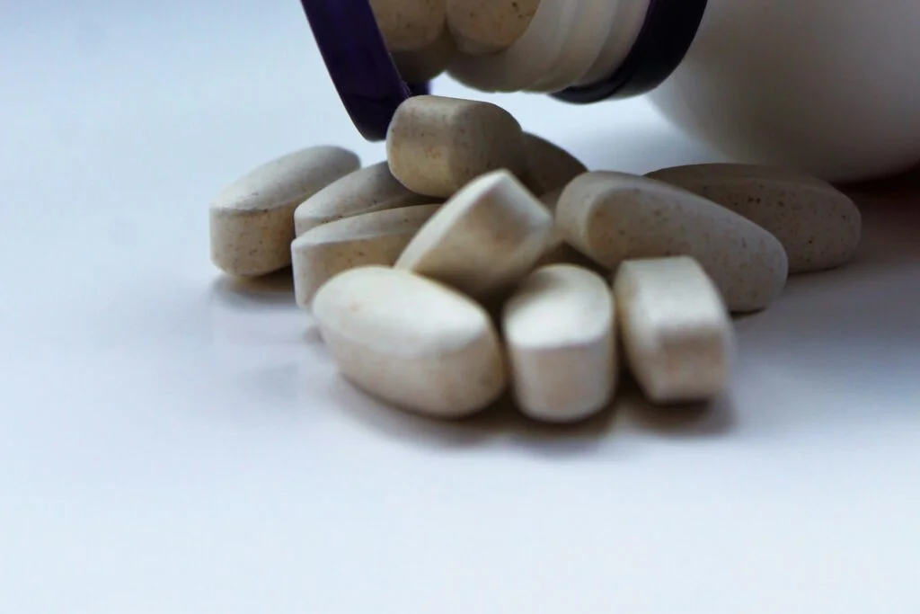 Magnesium tablets spilling from an open supplement bottle