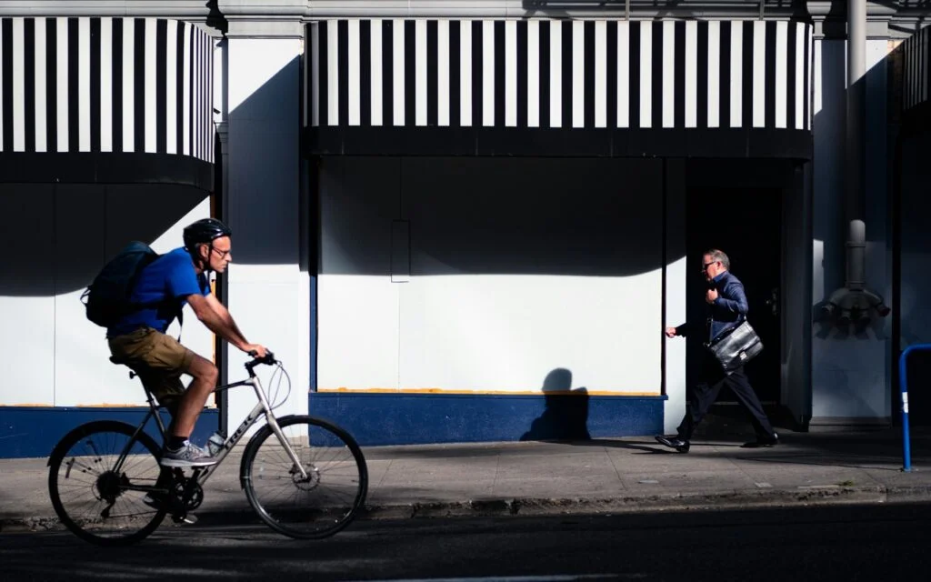A man cycling home along a sunny city street