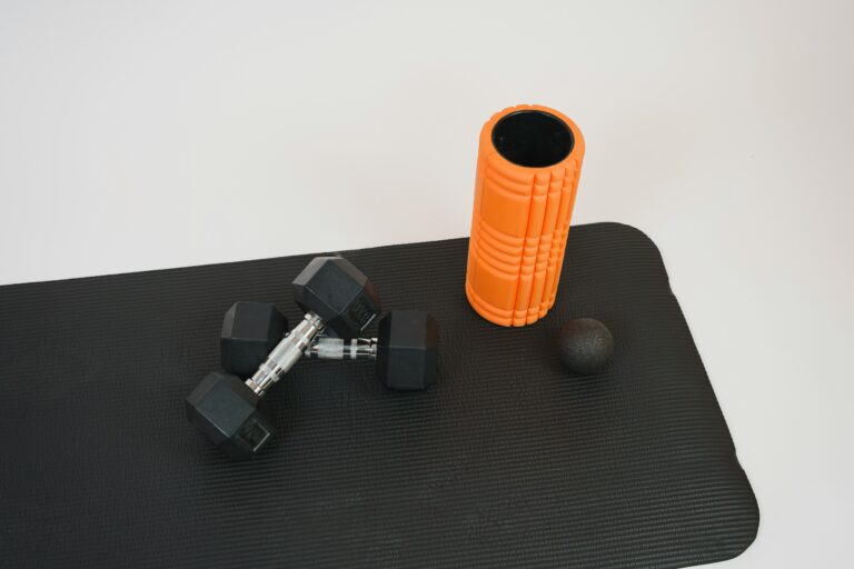 a black mat with a pair of dumbbells and a foam roller