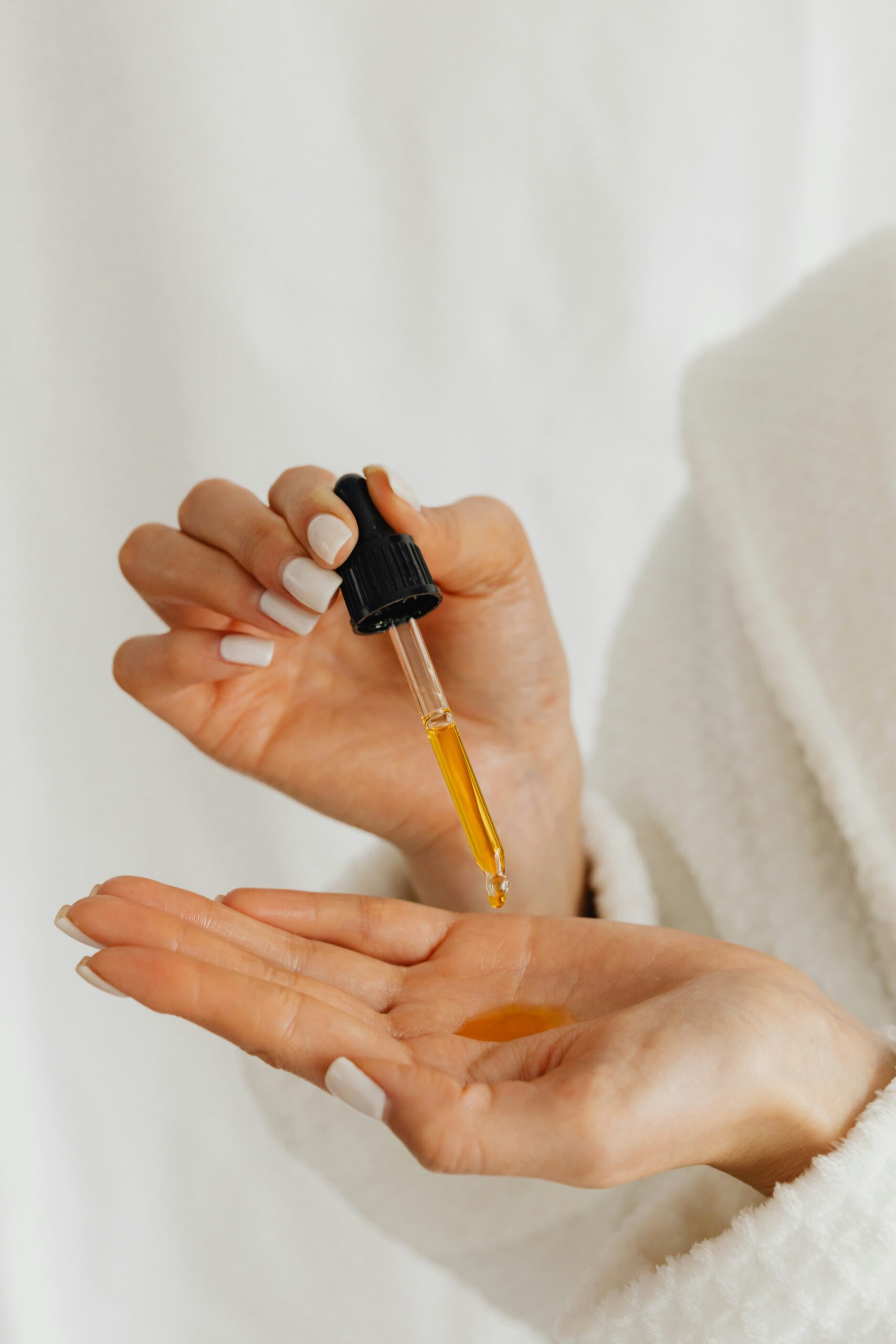 A woman holding a pipette with oil in hand