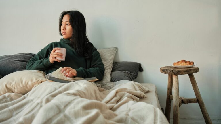 a woman in bed holding a drink