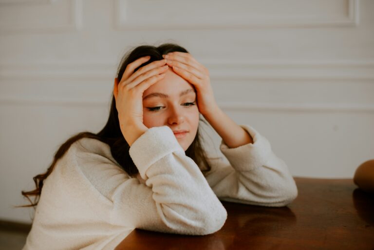 a woman sitting at a table with hands on her head