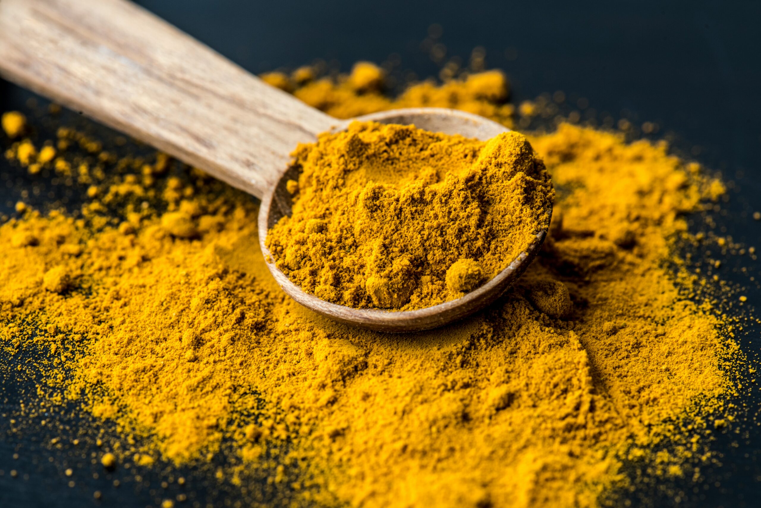 Close up of Tumeric powder on a wooden spoon