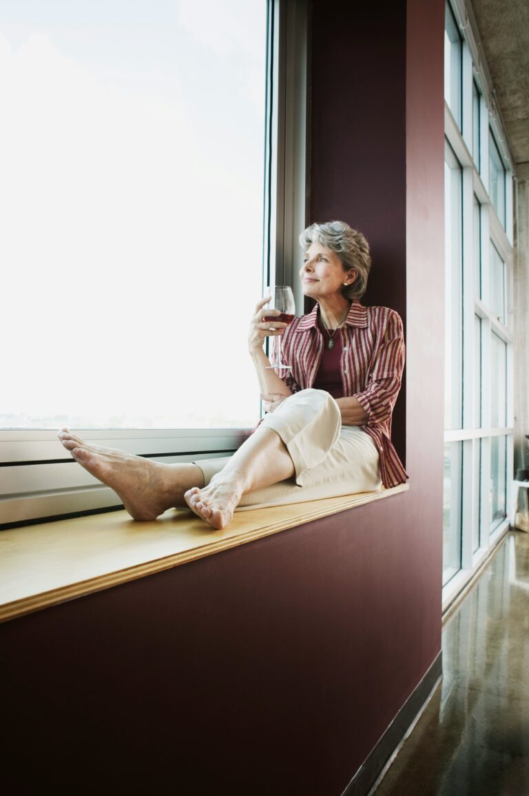a woman sitting on window sill looking outside