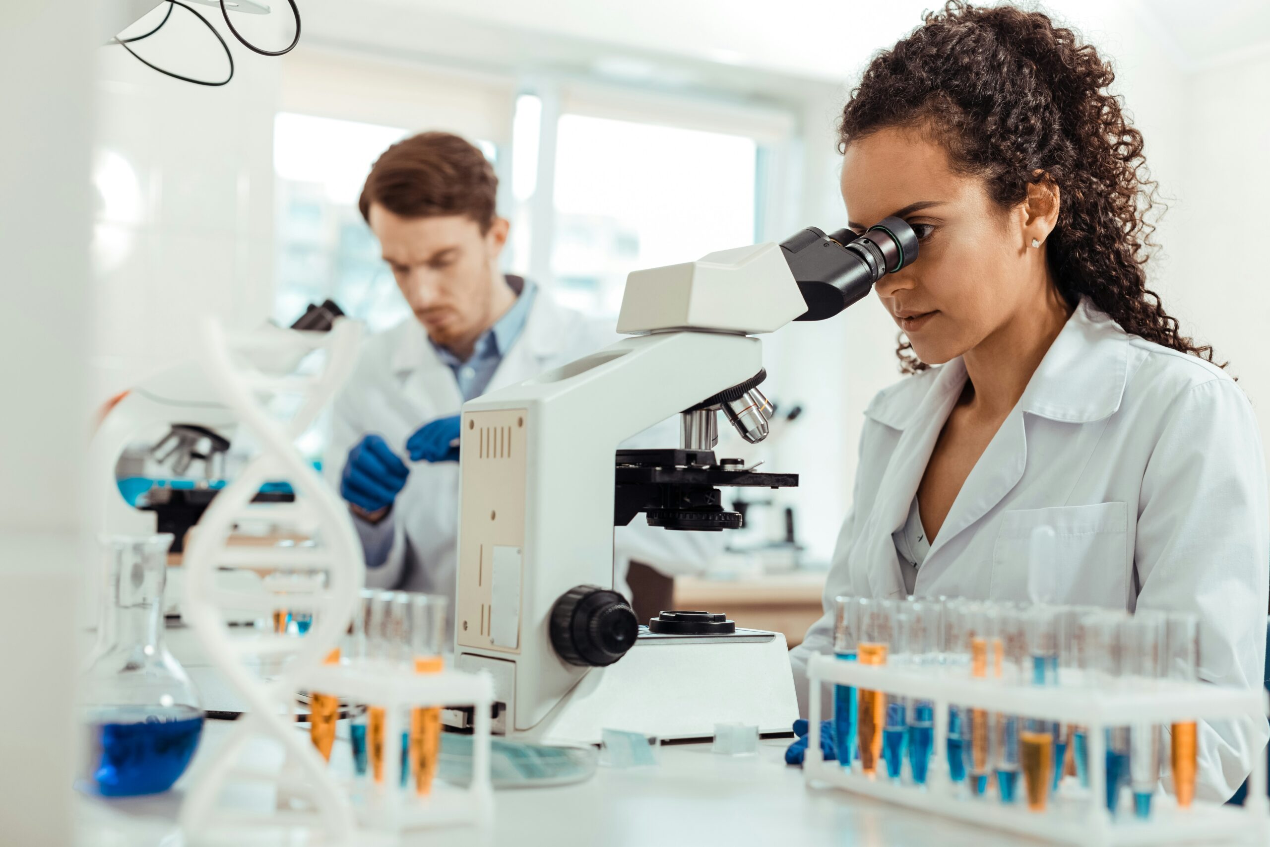 smart female biologist looking into microscope