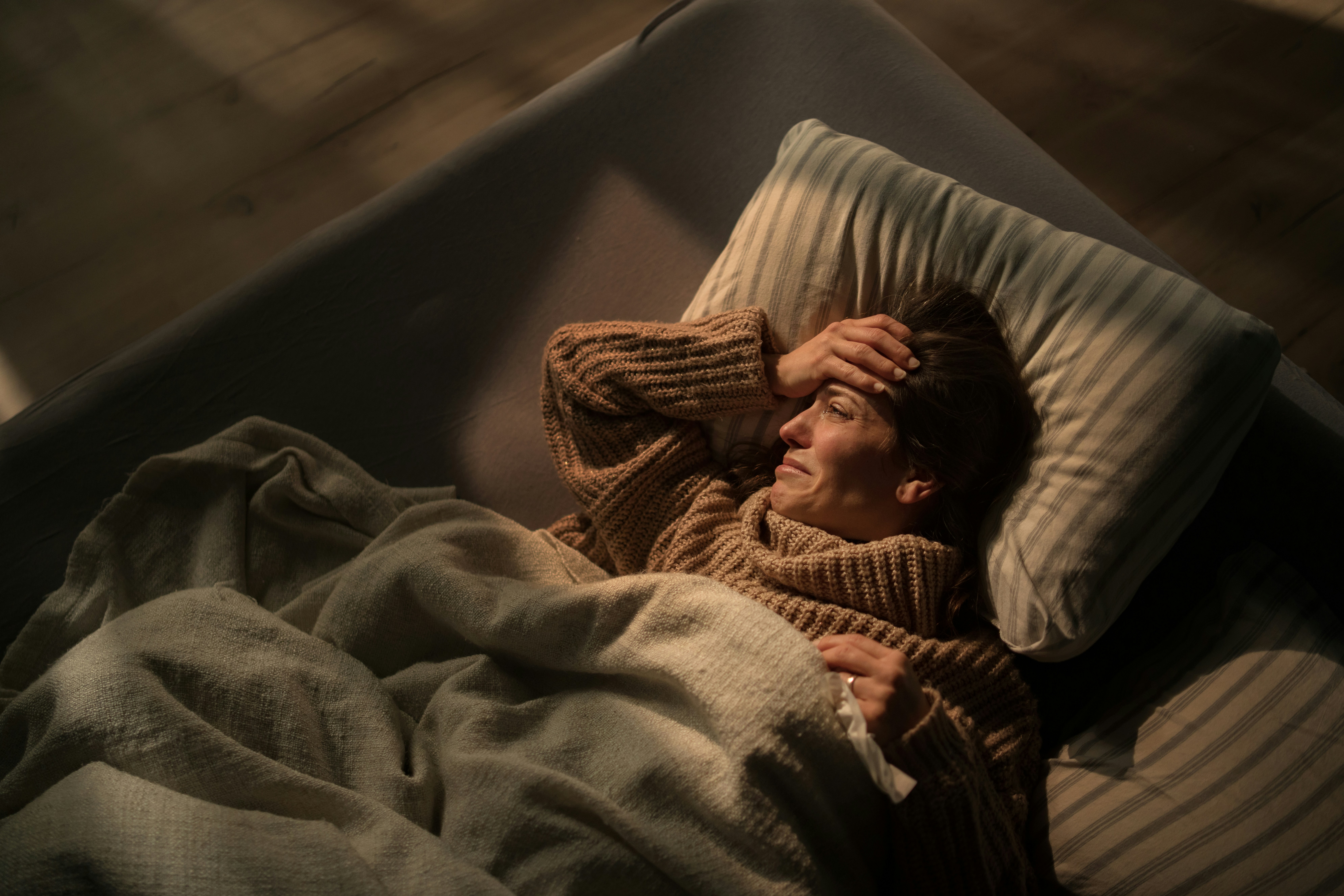 A close up of a woman struggling to sleep lying in bed at night